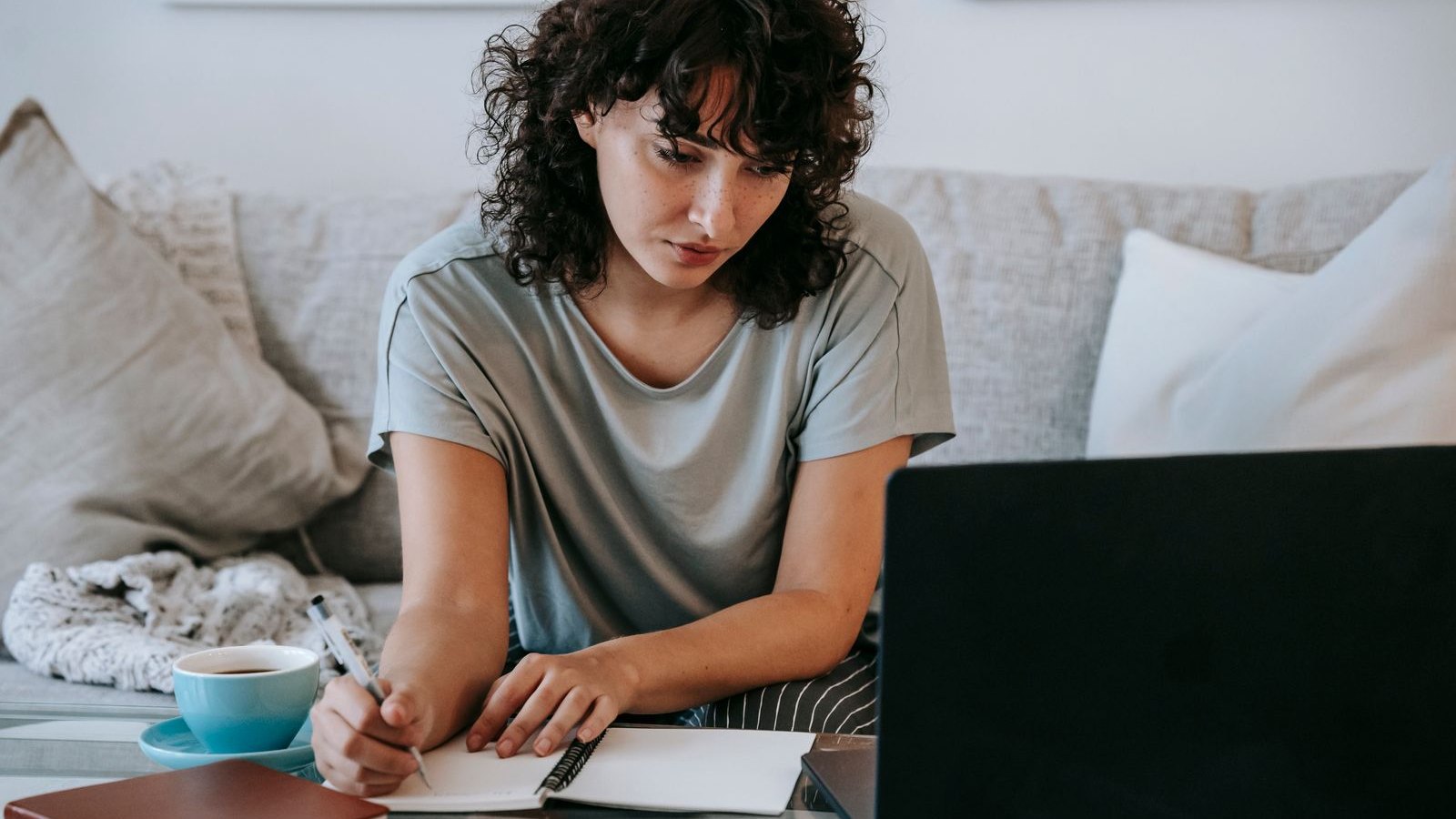 Kobieta notująca podczas szkolenia online przy laptopie