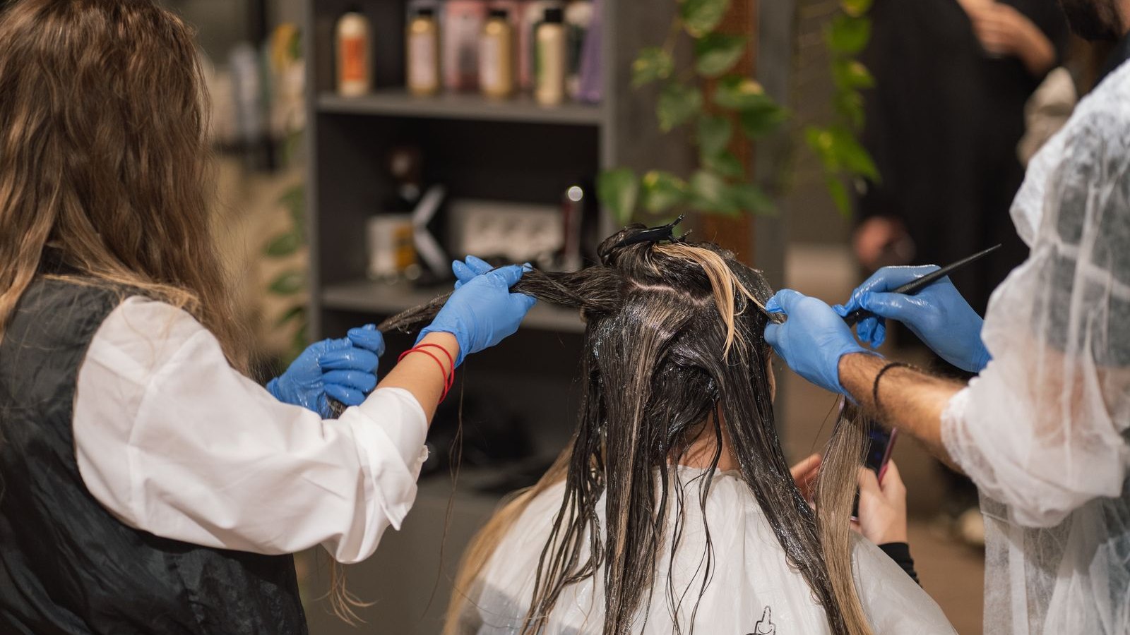 Dwie stylistki fryzur pracują razem nad fryzurą klientki w nowoczesnym salonie